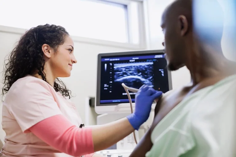 An Ultrasound Technologist Moving Transducer Over Patient's Shoulder