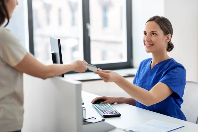 Receptionist Taking Patients Health Insurance Information During Check In