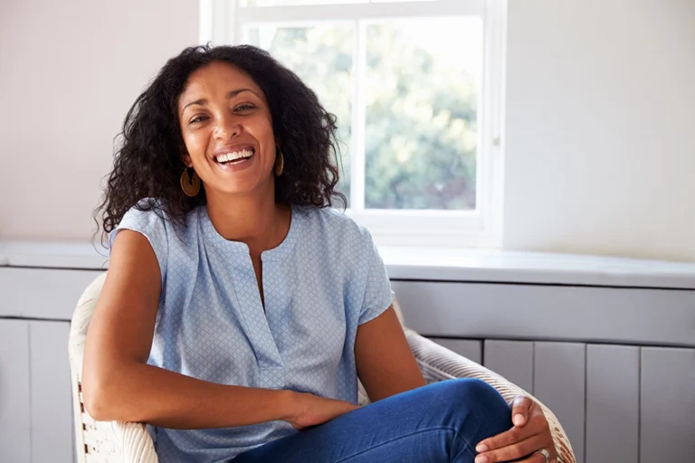 Woman In Her 40s Sitting In Chair Smiling