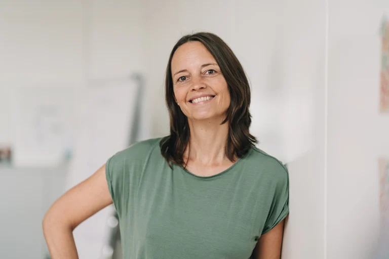 Happy Woman In Her 40s Leans Against Wall