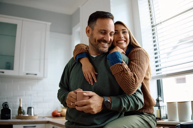 Happy Couple Embracing In Kitchen After Abdominal CT Scan Relieves Stress