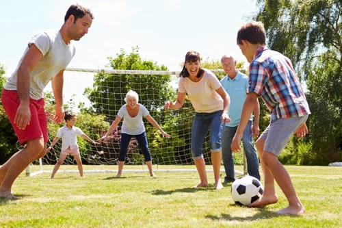 Happy Family Playing Soccer At The Park